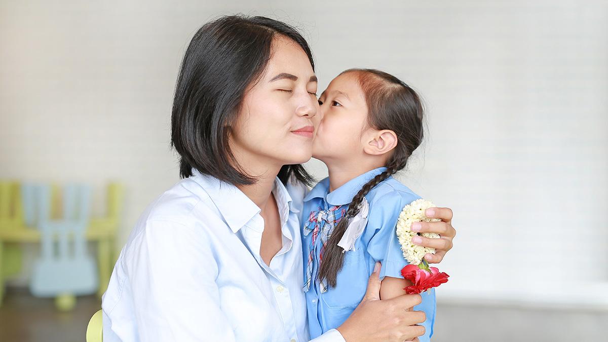 Portrait Asian little girl kissing her mom and hugging on Mother's day in thailand. Kid Pay respect and give Thai traditional jasmine garland to mother.