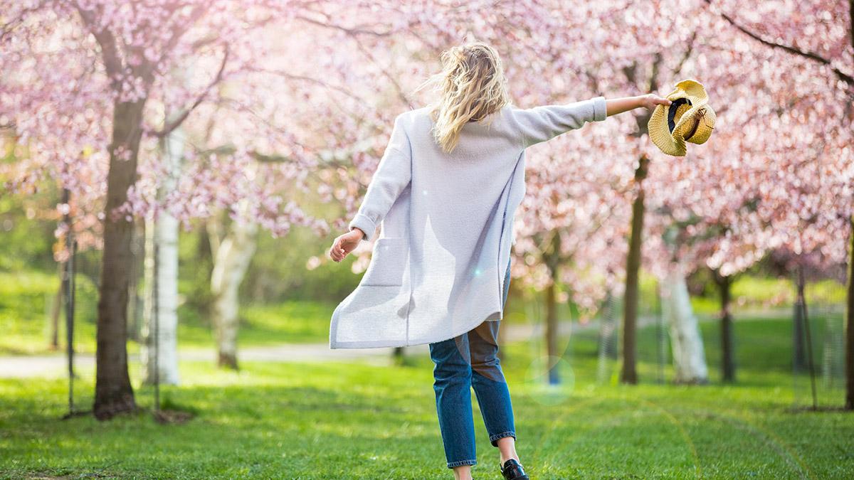 Young woman enjoying the nature in spring. Dancing, running and