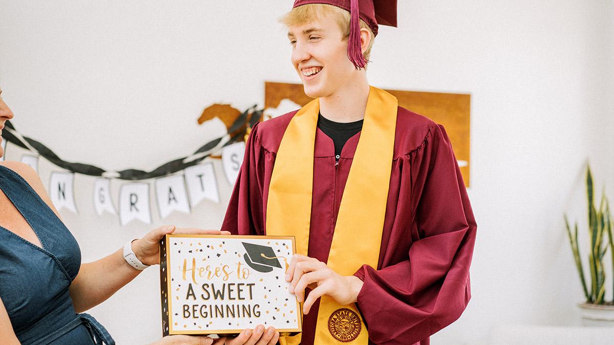 young man receiving a graduation gift from mother