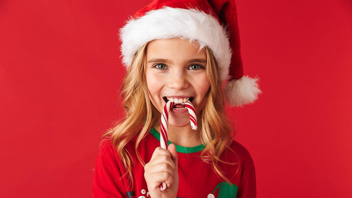 history of peppermint girl in santa hat eating candy cane hero