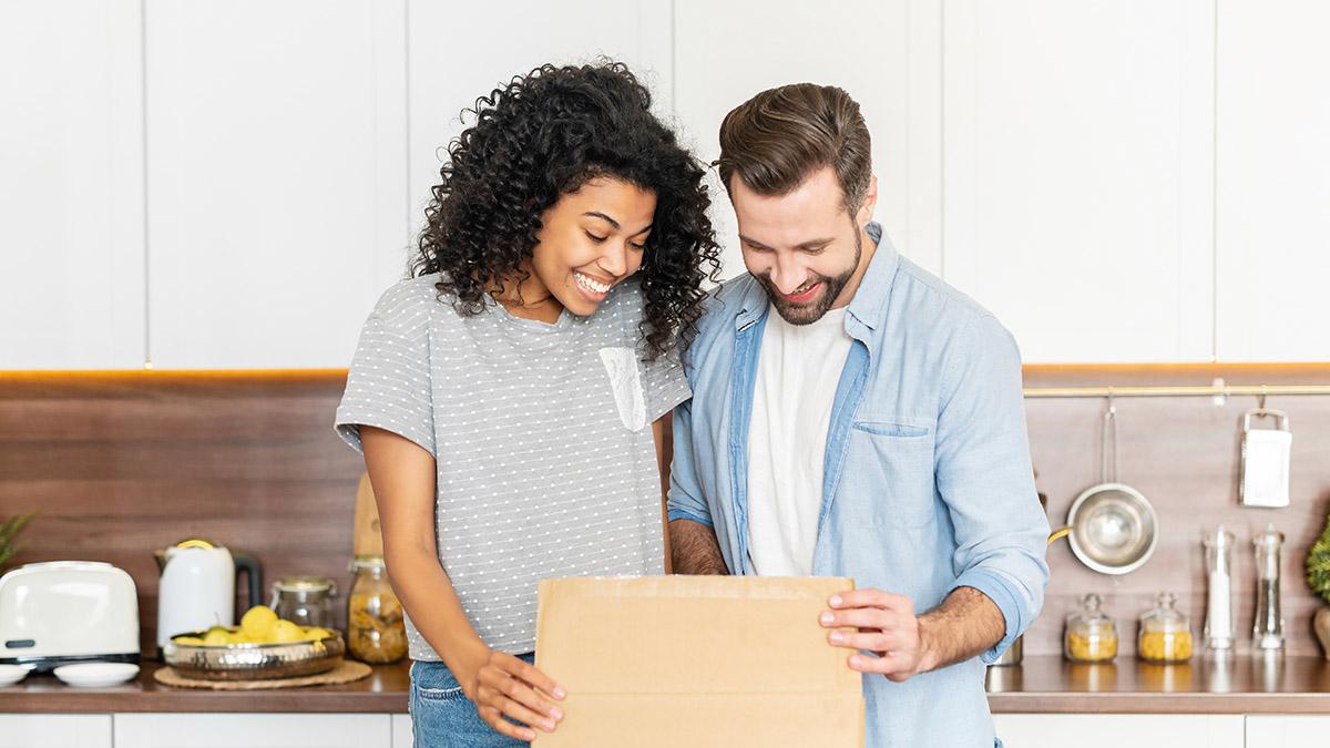 Happy interracial couple opening a carton box