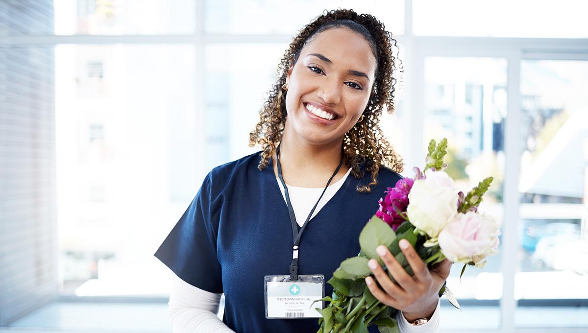 Success, celebration and portrait of doctor with flowers at a hospital for promotion and gift for work. Care, happy and female nurse with bouquet as a present for commitment in healthcare nursing job