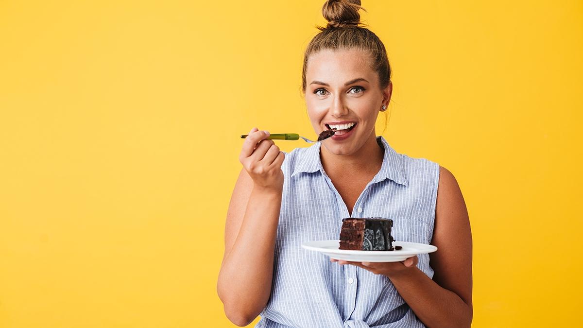Young smiling woman in shirt happily looking in camera while eat