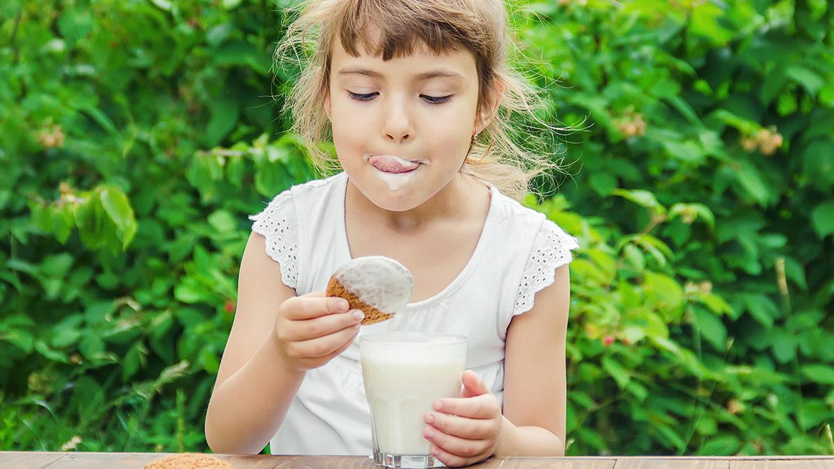 girl dipping cookies in milk
