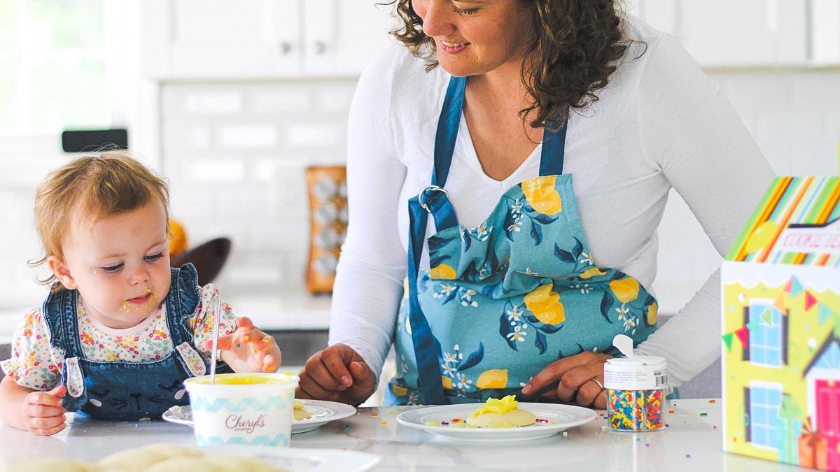 mother decorating cookies with young daughter