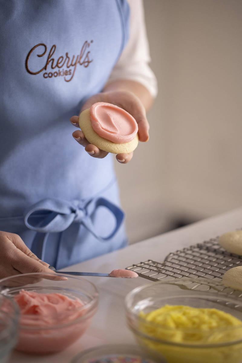 Photo of a woman spreading buttercream frosting on cookies