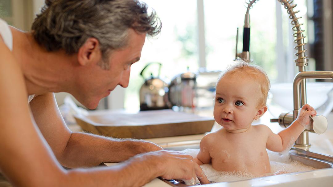 a photo of advice for new parents: dad bathing baby