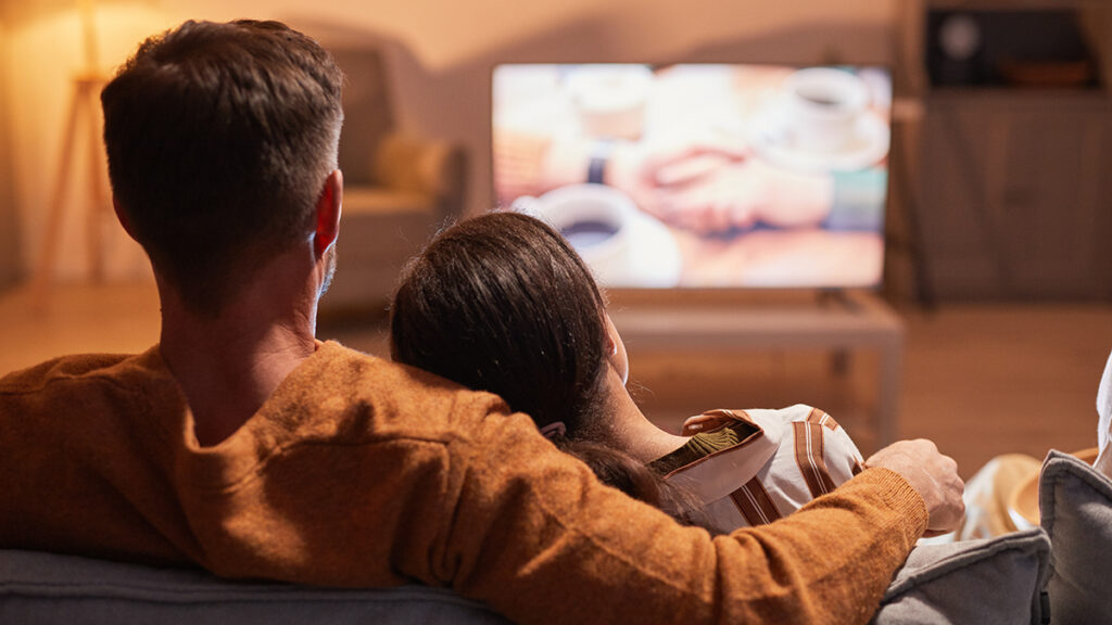 Couple enjoying a date night at home watching a movie on the couch.