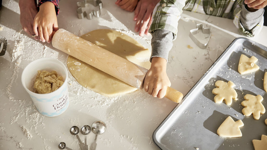 History of Christmas cookies with small children rolling out dough to cut into shapes.