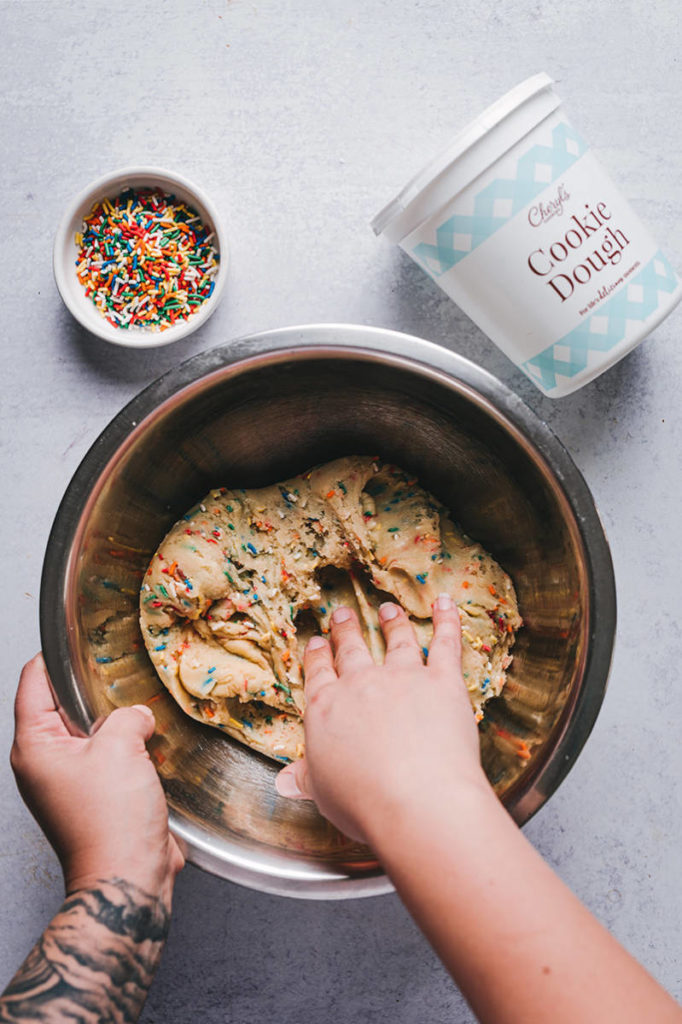 Cheryl's Cookie Dough with sprinkles being mixed in a bowl by hand