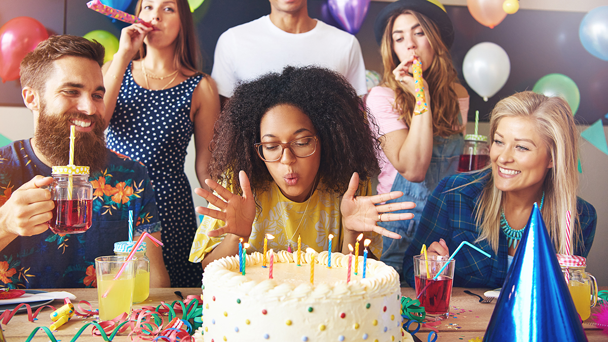 a photo of birthday traditions: woman blowing out candles