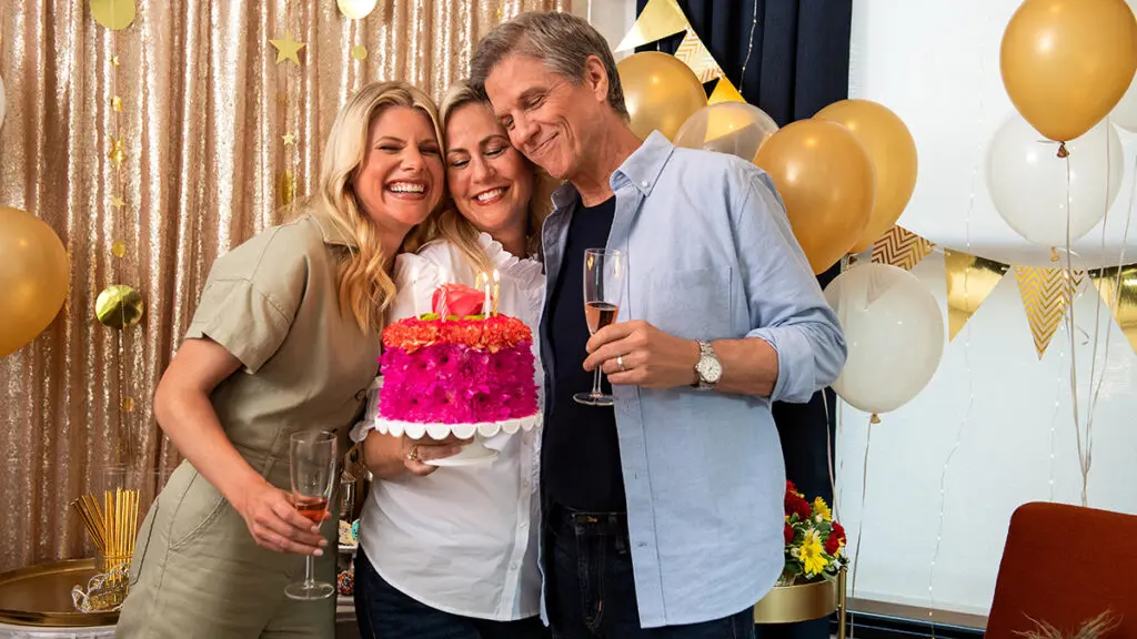 50th birthday ideas couple and a friend smiling at a birthday cake.